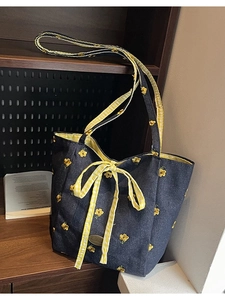 Blue denim tote bag with yellow floral embroidery and checkered bow ribbon accents