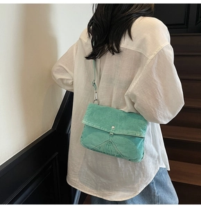 Detail of mint green denim crossbody bag with silver buckle worn by a model