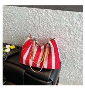 Detail of red and white striped mesh tote bag with leather handles and silver chain