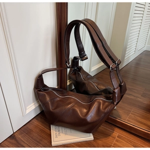 Detailed close-up of dark brown leather hobo bag with stitched panels and silver buckle