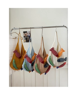 Detail view of colorful knitted tote bags with cute stuffed fish charms on a metal rack