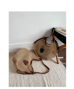 Detail view of woven straw tote bags with leather trim in brown and black finishes