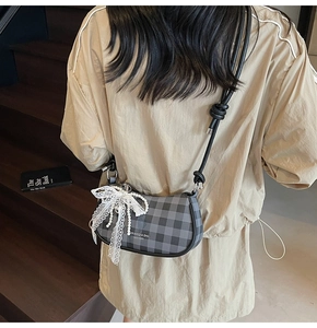 Détail du sac à bandoulière à carreaux gris avec nœud en dentelle et pendentif en perle