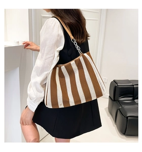 Detail of brown striped knit tote bag with leather strap and silver metal chain detail