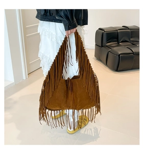 Brown suede tote bag with long tassels shown on a model in a minimalist modern setting