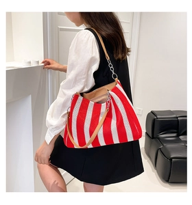 Detail view of red and white striped woven tote bag with brown leather strap and chain