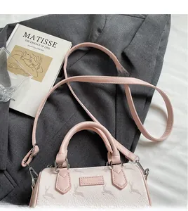 Detail of elegant printed Boston bag with smooth leather strap next to an art book
