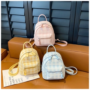 Close-up of three mini plaid backpacks in pink, yellow and blue with front zip pockets