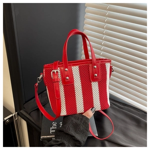 Détail du sac seau tissé à rayures rouges et blanches avec poignées en cuir et rivets
