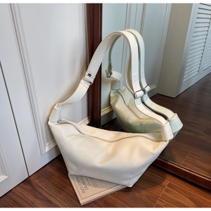 Detailed close-up of white crescent shoulder bag with wide strap and silver metal buckle