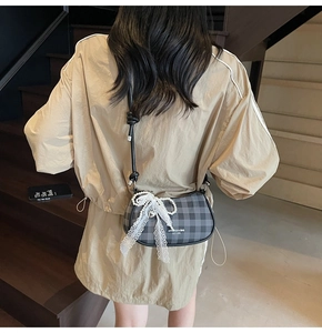 Détail du sac à bandoulière à carreaux avec nœud en dentelle et breloque perle