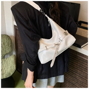 Close-up of white glossy underarm bag with decorative belt buckle and wide strap