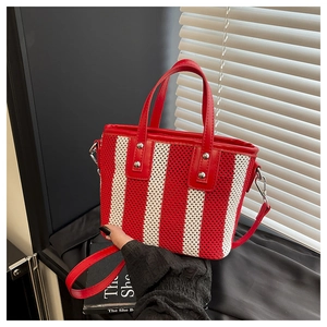 Détail du sac seau tissé à rayures rouges et blanches avec poignées en cuir et rivets