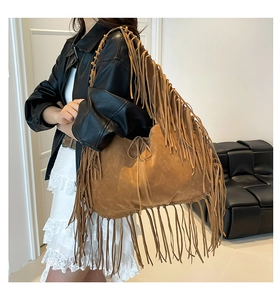 Detail of a large brown suede tote bag featuring long bohemian style fringe and tassels