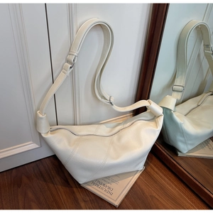Detailed macro view of cream-colored dumpling bag with stitching and adjustable strap
