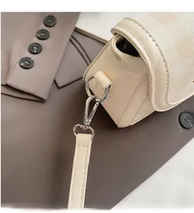 Close-up of silver metal hardware and fine leather texture on beige shoulder bag