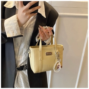 Dettaglio mini borsa a secchiello gialla con trama litchi e ciondoli di perle
