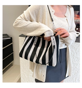 Detail of silver chain strap and black leather on striped woven tote bag
