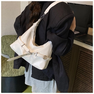 Detail of white glossy underarm bag with metal buckle and shoulder strap on model