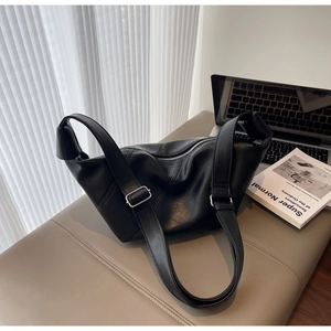 Detail of minimalist black leather hobo bag with adjustable silver buckle on soft bench