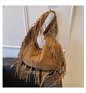 Detail shot of a bohemian brown suede fringe hobo bag on a black sofa
