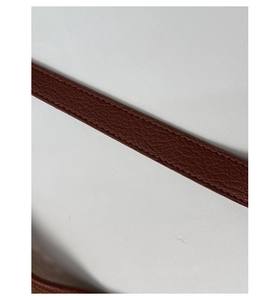 Close-up of brown lychee grain leather strap with refined stitching on woven bag