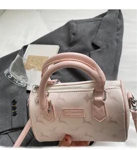 Detailed view of pink Boston bag with deer prints resting on a grey blazer suit