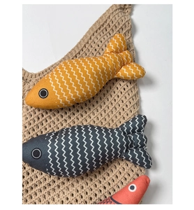 Detail of fish-shaped cotton plush charms with zigzag patterns on a knit base