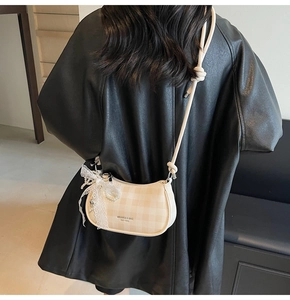 Vue détaillée d'un sac bandoulière à carreaux beige avec breloques en perle et dentelle