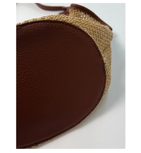 Detail showing the brown lychee leather base and woven straw texture of the beach tote