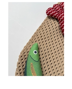 Close-up detail of green fish fabric accessory on a woven knit tote bag with texture