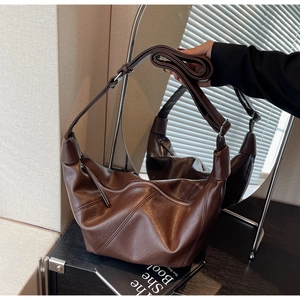 Detail of deep brown crescent bag showing lychee grain leather texture and adjustable strap