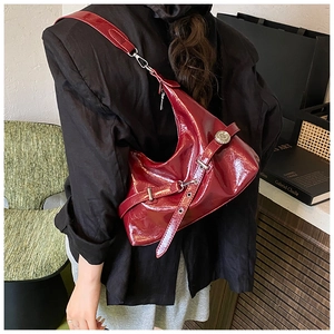 Detail of burgundy glossy leather underarm bag with metal buckle and hobo style shape