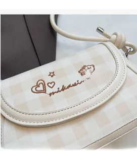 Close-up of checkerboard pattern bag with bear embroidery and leather shoulder strap