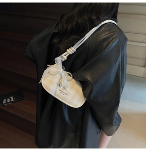 Détail du sac à carreaux avec nœud en dentelle, chaîne en perles et pendentif cœur argenté