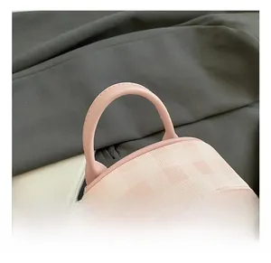 Detailed close-up of pink plaid backpack featuring leather handle and silver zipper