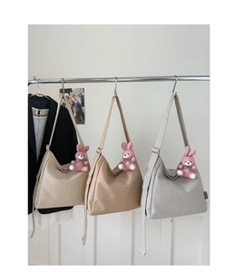 Detail of khaki and grey canvas tote bags with plush bunny charms on hangers