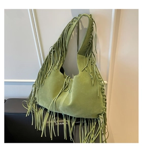 Close-up of olive green suede tote bag featuring bohemian tassels and braided details