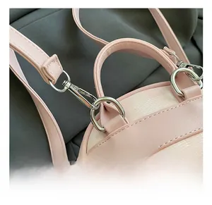 Close-up of premium metal swivel hooks and leather handle on pink plaid backpack