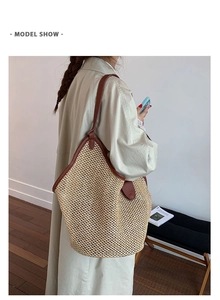 Detailed view of a large straw tote bag with brown leather handles worn by a model