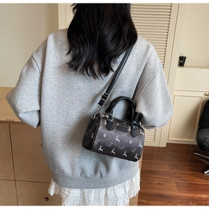 Deep brown Boston bag with white deer print shown on a model in a cozy indoor setting