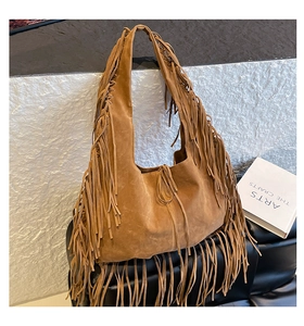Detail shot of brown suede fringe shoulder bag with bohemian tassels in a studio setting