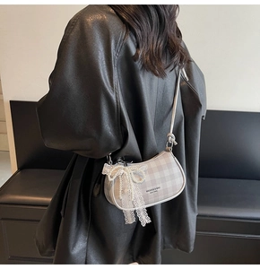 Détail du sac demi-lune à carreaux gris avec nœud en dentelle et breloque en perles