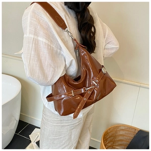 Detail of glossy patent leather dark brown hobo bag with adjustable silver buckle strap