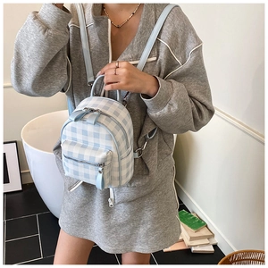 Détail d'un mini sac à dos à carreaux bleu clair avec fermetures éclair argentées et sangle