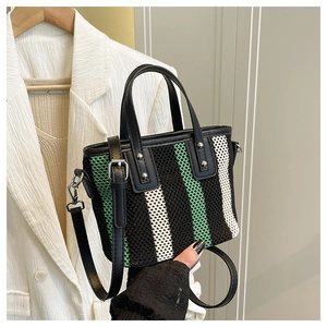 Détail d'un sac cabas tissé à rayures avec poignées en cuir et rivets argentés