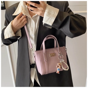 Dettaglio della mini borsa tote lavanda grana litchi con ciondolo a perla e cartone
