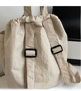Detail of beige drawstring backpack showing adjustable straps and smooth nylon texture