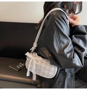 Détail du sac à carreaux gris avec nœud en dentelle blanche et chaîne de perles