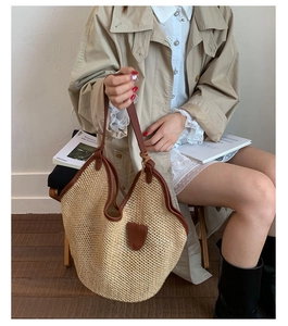 Close-up of beige woven straw tote with brown leather handles and wavy trim detail
